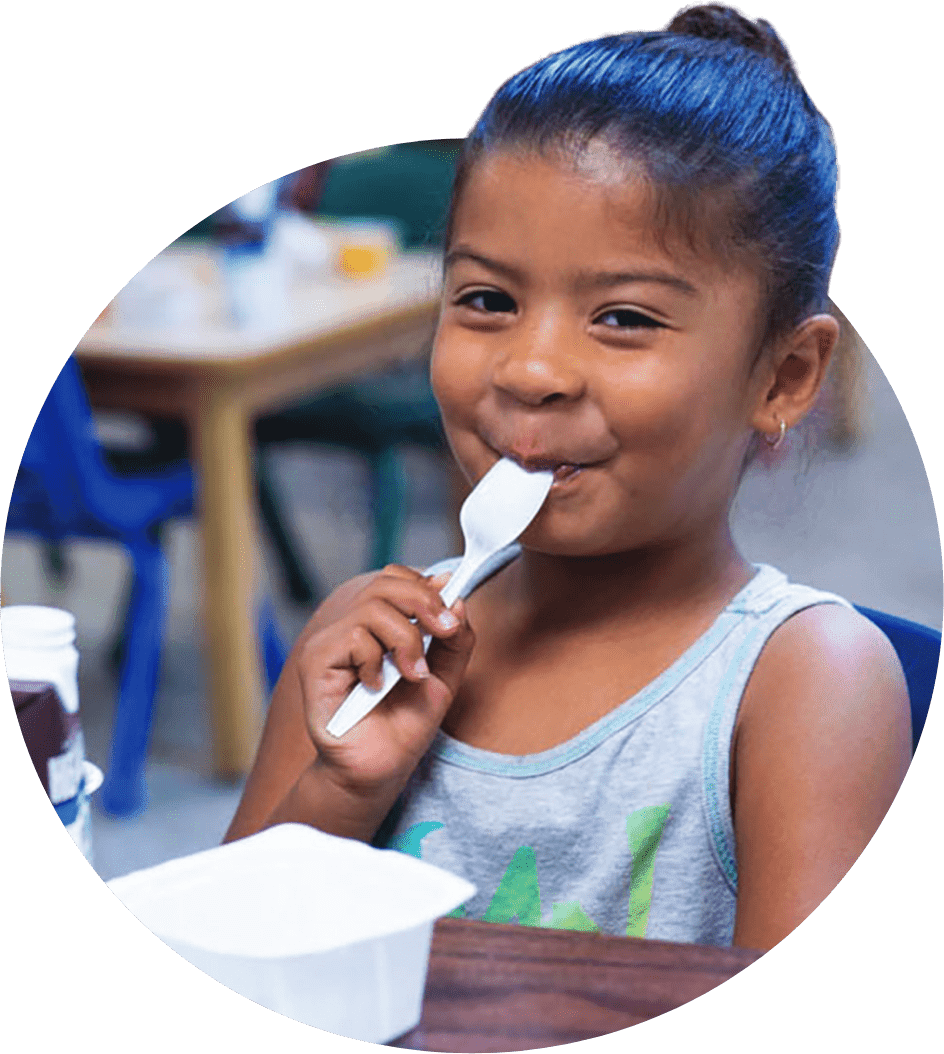 A young girl eating yogurt